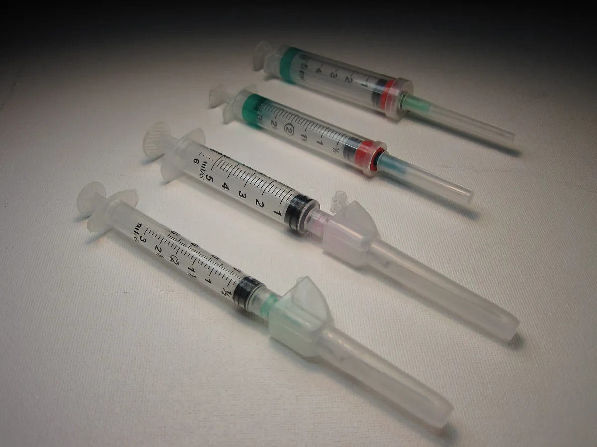 Several capped syringes with needles laid on a white surface