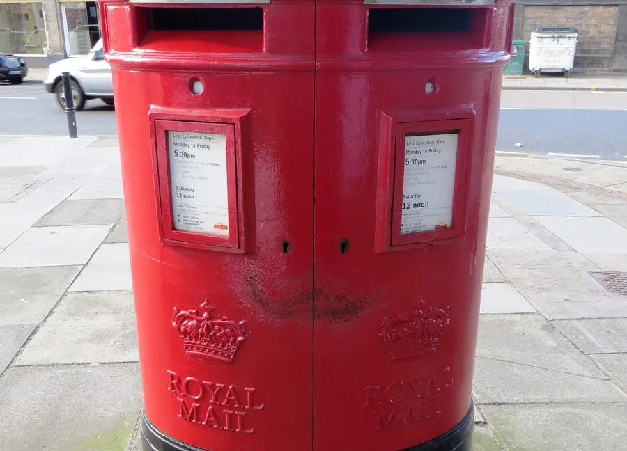 A red Royal Mail pillar box on a city street