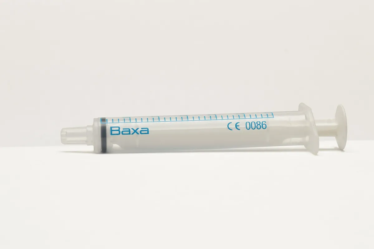 A clear plastic syringe on a white surface