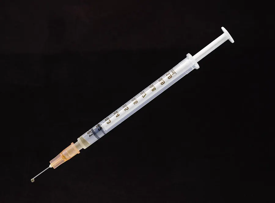 A luer-lock syringe against a black background
